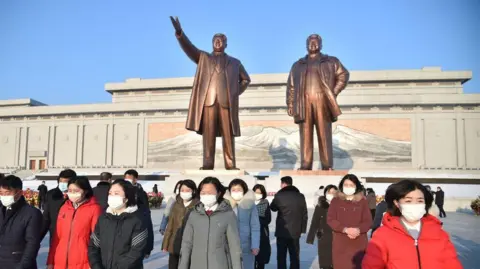 Getty Images In this photo taken on February 16, 2022, people visit the bronze statues of former President Kim Il Sung 