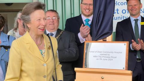 Princess Anne smiling as she stands next to a plaque which reads "Forest of Dean Community Hospital opened by HRH The Princess Royal on 7th June 2024"