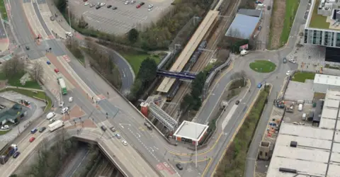 Network Rail An aerial view of Salford Crescent station, showing a train at one of its platforms, which runs beneath a dual carriageway