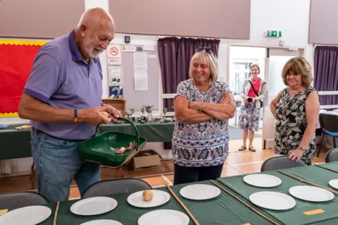 Jim Grover People place vegetables on plates ahead of the opening of the show