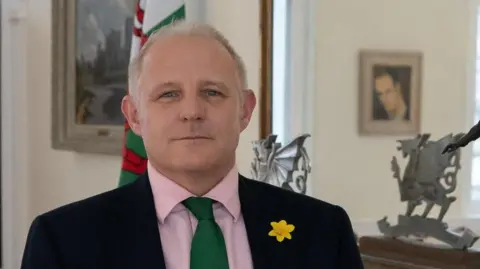 UK Government Veterans Commissioner Colonel James Phillips standing in front of a Welsh flag.