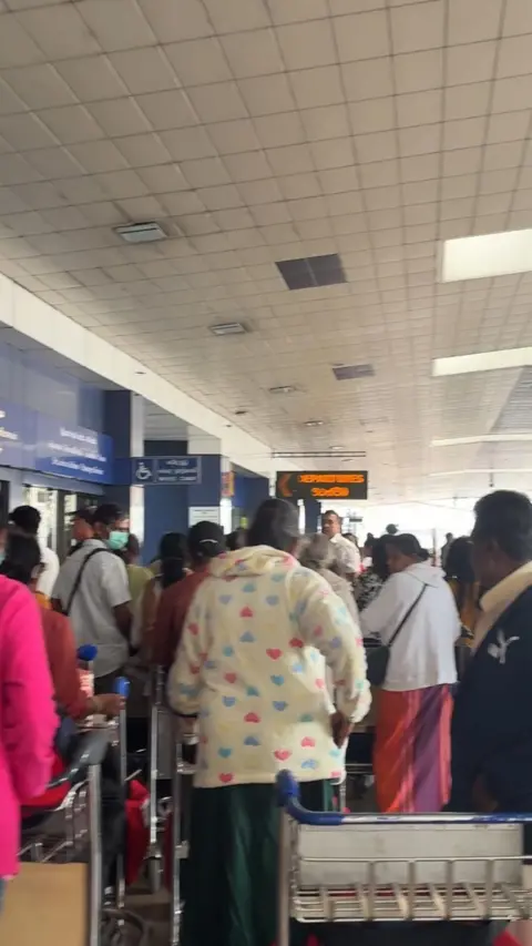 Yasmin Rufo People wearing casual outfits queue outside the airport with their cases