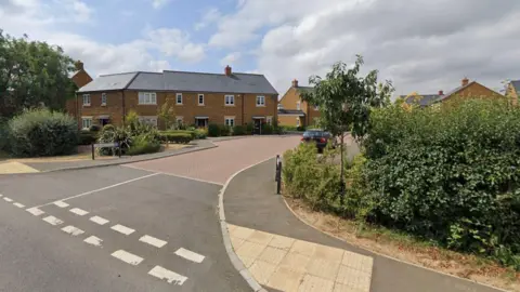 A google street view image of a T-junction from a small side road into a long straight main road