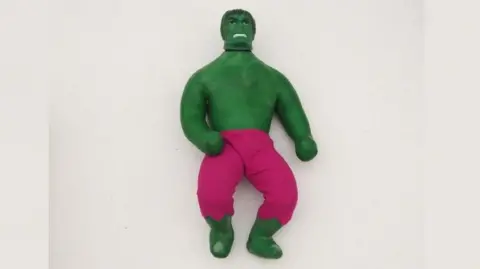 PA Media A green Hulk character is in the middle. The toy is a stretchy one, and Hulk is painted green and wearing pink trousers.