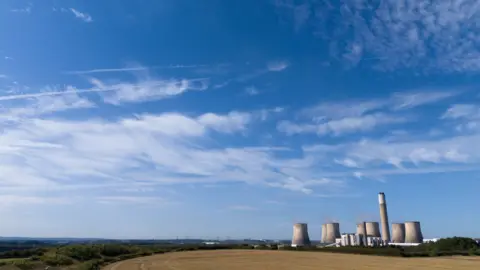 PA Media Ratcliffe-on-Soar power station in the middle distance, with blue skies overhead and fields surrounding it