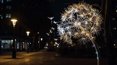 Visit Blackpool The Wish artwork - a glowing, interactive installation made up of giant dandelions, captured just as they are about to scatter - on display in Blackpool at night.