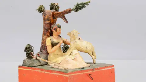 Special Auction Services A Sonneberg  papier-mache and wood hand-cranked mechanical toy of a shepherdess.

