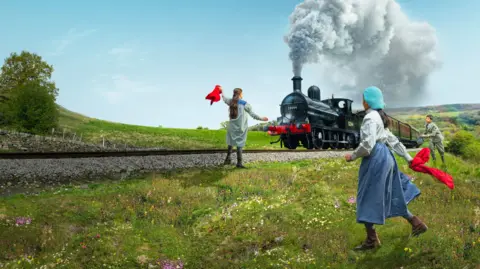 Guy Farrow Three children playing on grass with a steam train going by
