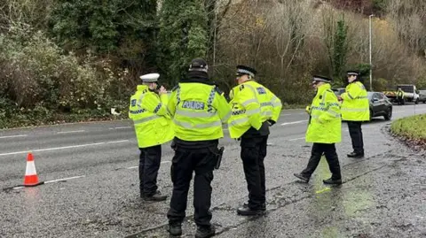 George Carden/BBC Five police officers in hi vis are standing in the road