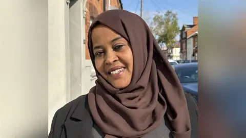 Fartun Ismail wearing a brown hijab and black suit jacket standing in a street.