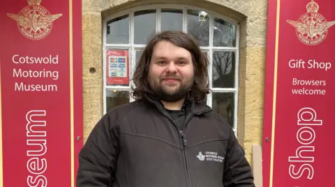 A photo of Adam Grime stood outside the front of the Motor Museum in Bourton-on-the-Water.