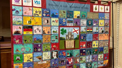 A patchwork quilt memorial to victims of the Troubles. At the top it says: 'Diversity in Life, Remembered in Unity'.