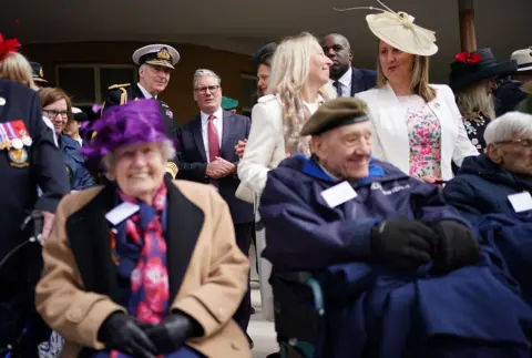 PA Media Prime Minister Sir Keir Starmer is pictured speaking with veterans, with other veterans and onlookers surrounding them, in front of Buckingham Palace during the procession.