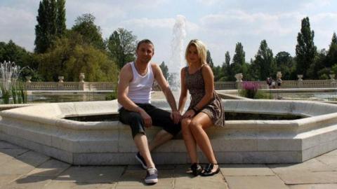 Stevie and Tanya Kordek sit in front of a water fountain.