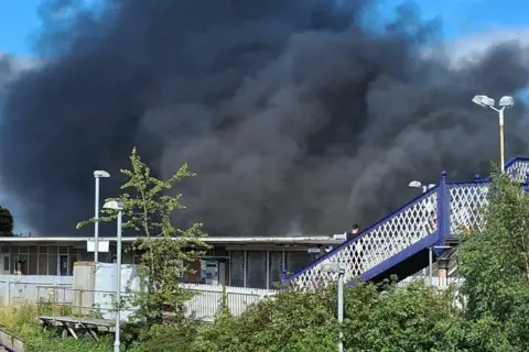 Fife Jammer Locations A large cloud of black smoke fills the sky above a railway station bridge.