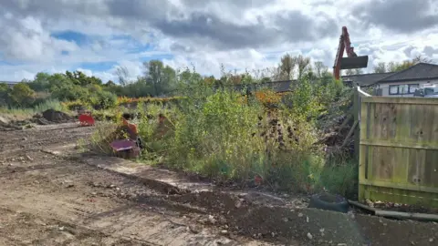 LDRS Weedy and muddy scrubland on the current site with a digger in the background