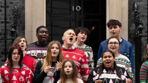 PA Media Liberal Democrat leader Sir Ed Davey with the Bath Philharmonia Carers' Choir performing their charity single Love is Enough, outside Number 10