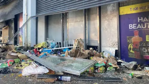 PA Media Smashed debris outside shops in Belfast