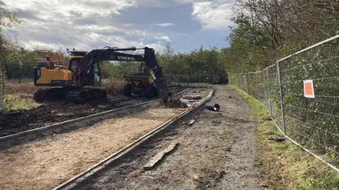 Supplied Two yellow diggers parked at the construction site of the path, which is fenced off.