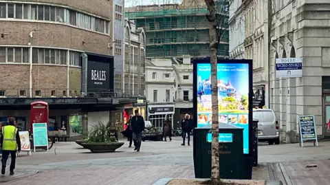 A high street with empty shops and people walking up and down the street. 