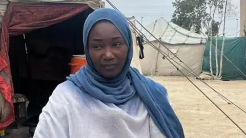 Woman in a blue headscarf looks to her right.
