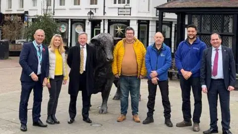 Hereford BID A group of people stand next to a statue of a bull and smile at the camera