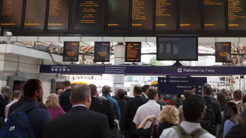 A stock image of passengers waiting by the departures boards at Victoria Station in London