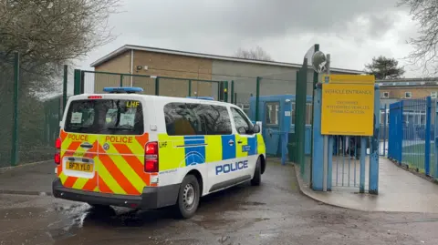 A police van parked outside the gated vehicle entrance to Kingsbury High School.