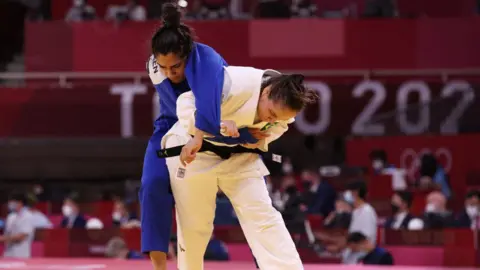 Getty Images Brazil's Maria Portela (white) and Refugee Olympic Team's Nigara Shaheen compete in the judo women's -70kg elimination round bout during the Tokyo 2020 Olympic Games at the Nippon Budokan in Tokyo on July 28, 2021. 