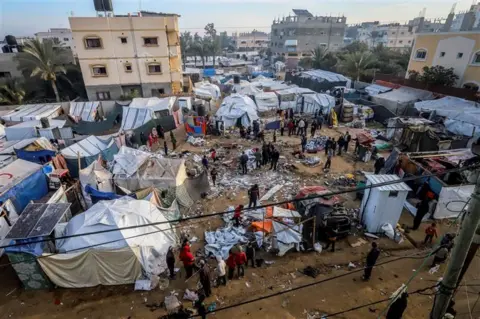 Saeed Jaras / AFP melalui Getty Images Warga Palestina memeriksa tenda-tenda yang rusak untuk pengungsi menyusul serangan di Deir el-Balah, Jalur Gaza, pada 4 Januari 2025.