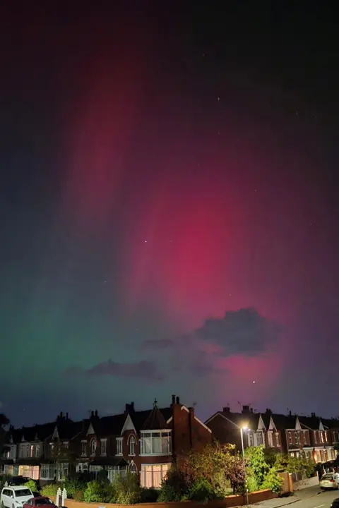 Eva A darker sky is also split in dark green and purple-pink above a street of houses in Southport