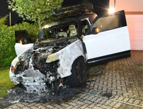 Crown Office and Procurator Fiscal Service The burned out remains of a white Land Rover, parked on a suburban driveway.