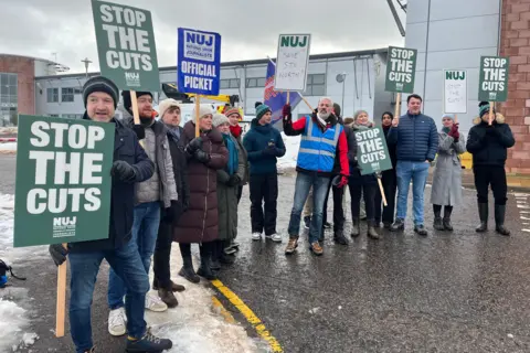 STV staff on the picket line in Aberdeen. They are all wearing warm winter clothing and holding "Stop The Cuts" placards.