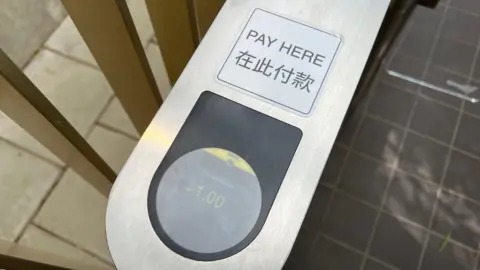 A view of the silver payment tower from above. It says "Pay Here", with Chinese writing underneath.