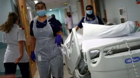 PA Media Medical staff transfer a patient through a corridor at The Royal Blackburn Teaching Hospital