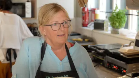 Sarah Bridges standing behind the counter in her sandwich shop.