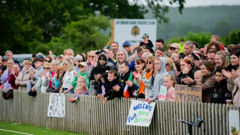 Millie Evans A large crowd of people with signs standing behind a low wooden fence