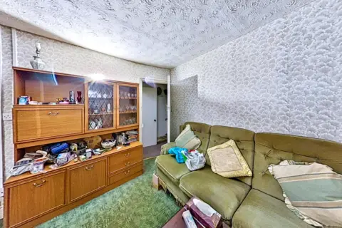 Paul Fosh Auctions A living room is pictured with a sofa, pillows and a wooden cabinet