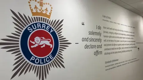 LDRS A Surrey Police badge with a motto on the wall.