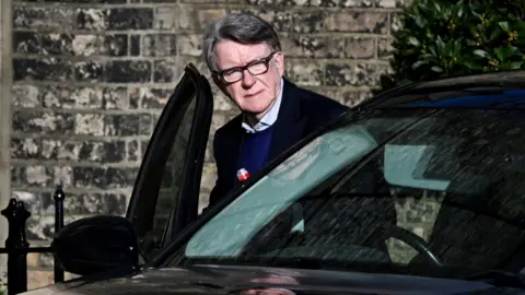 Reuters Lord Mandelson is pictured entering a car outside his home, he is opening the door, against a brick facade background. Taken in London on 14 February.