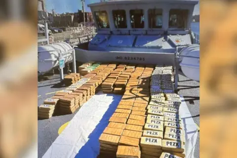 drugs in packages on a boat, they are in brown packages all on top of one another.