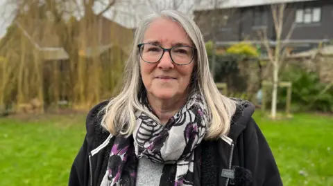 David Reeves/BBC A woman standing in a garden looking into the camera.