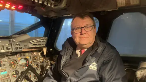Photograph of Concorde tour guide Steve Edwards. He is pictured on the flight deck of the plane at the Manchester Airport Runway Visitor Park.