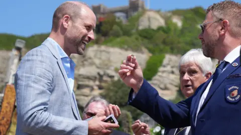 Prince William beams as he receives his silver winkle charm from the Hastings Winkle Club