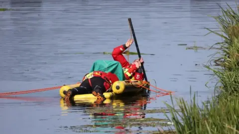 Shaun Whitmore/BBC Police divers in a lifeboat dinghy searching the water