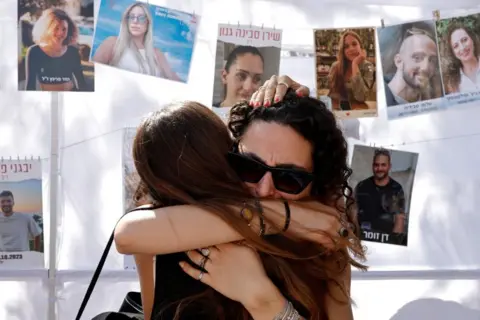 Two women hug in grief at the site of the Nova festival attack, on 7 October 2025