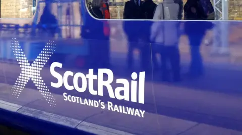 A Scotrail train carriage, painted blue with white lettering saying Scotrail, with Scotland's Railway written underneath it