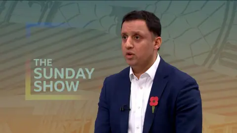 Anas Sarwar, a dark haired man wearing a dark blue suit and white shirt