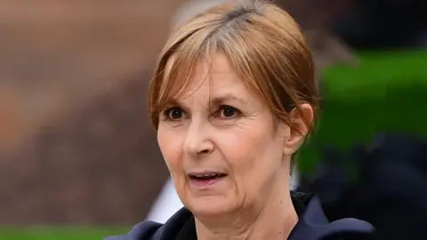 Mirrorpix Joanne Sharkey with brown hair tied back and brown eyes wearing a navy coat