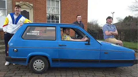 Harry Atkinson (far left) stood next to the powder blue Reliant Robin, with his three friends who joined him on the trip